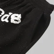 Close-up view of the black Sp5der Vvs sweatshorts featuring all-over tonal rhinestone detailing and signature branding.