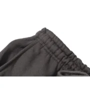 A close-up view showing the elasticated waistband detail on the slate green Sp5der Wait Web streetwear sweatpants.