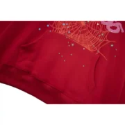 Close-up view of the front pocket graphic on the red Sp5der Worldwide Angel Number 555 hoodie showing brand detail.