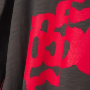 Detailed close-up of the grey Sp5der Contrast Stitch Slub Tee showing the textured fabric and red graphic print.