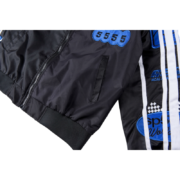 A close-up view of the Sp5der Satin Bomber Jacket showcasing detailed chest embroidery and blue athletic sleeve patches.