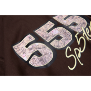 Close-up view of the minimalist Sp5der 555 graphic logo on a premium earthy brown streetwear cotton t-shirt design.
