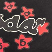 Close-up view of the black Sp5der Warped Tee featuring a distorted white graphic logo and vibrant red star accents.
