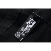 Close-up view of the interior clothing label featuring the iconic Sp5der web logo on a premium black t-shirt.