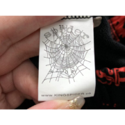Close-up photo showing the Sp5der Sex AOP Sweatpants brand tag with the iconic spider web logo and authentic label detail.