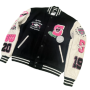 The SP5DER Division 5 Varsity Jacket features a premium black body with white sleeves and detailed embroidered graphics.