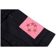 Close up of the Sp5der 5Star Vintage 501 black denim jeans showing the iconic pink branded star logo patch label.