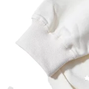 Detailed view of the ribbed sleeve cuff on the cream Sp5der x Mariah the Scientist Scorpion Hoodie streetwear garment.