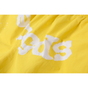 Close up of the Sp5der OG Web Double Layer Shorts in yellow featuring the iconic white graphic print detail.