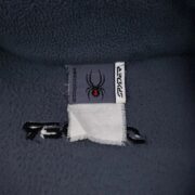 Close-up view of the Sp5der fleece jacket interior featuring the authentic brand neck label with spider logo and details.
