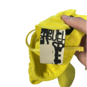 Close-up view of a yellow Sp5der OG Web double layer short featuring the signature brand tag and web graphic design.