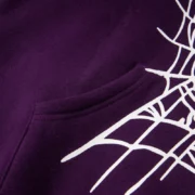 Close-up view of the purple Sp5der web hoodie featuring the iconic white web graphic print and kangaroo pocket detail.
