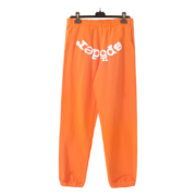 Front view of orange Sp5der Websuit sweatpants with white logo branding hanging on a clothing hanger for display.