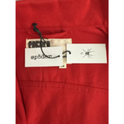 Close up view of the Sp5der Denim Jacket brand tag and spider logo on a vibrant red denim fabric background.