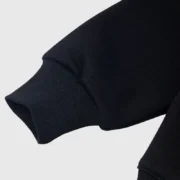 Close-up view of the ribbed sleeve cuff detail on the premium black Sp5der Heavy Web Hoodie, highlighting its quality.
