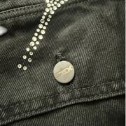 Close-up view of the Sp5der Worldwide Jacket showcasing custom metal branded hardware and detailed rhinestone trim.