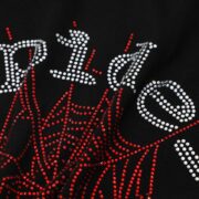 Close-up view of the Sp5der Thug T-shirt showing premium fabric with intricate red and white rhinestone web graphic details.