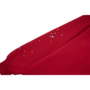 Close-up of the sleeve on a Sp5der Worldwide Red Angel Number 555 Hoodie featuring small star graphic details.
