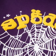 Close-up view of the purple Sp5der Star OG Web V2 hoodie featuring a prominent yellow puff print brand logo and web graphic.