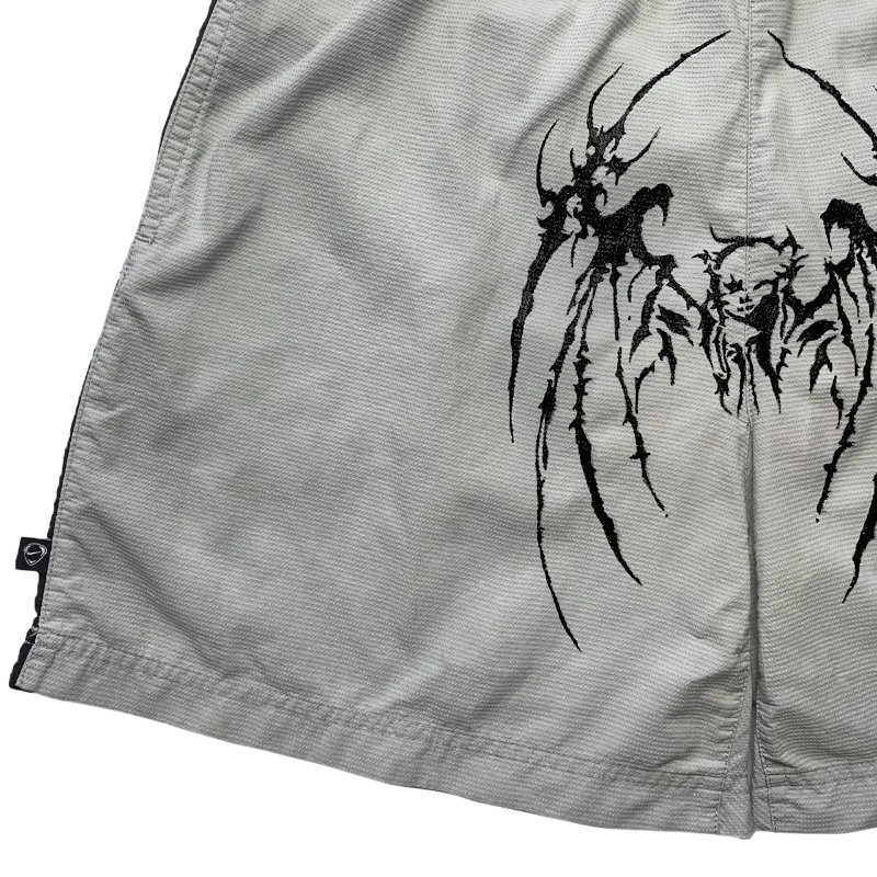 Close up view of the grey Sp5der print shorts featuring a distinctive black graphic design and elastic waistband.