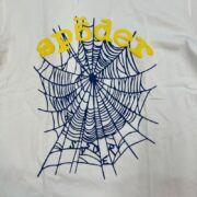 Close-up view of the Sp5der OG Web V2 white t-shirt featuring the iconic blue spider web graphic and yellow logo text.