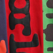 Close-up view of the Sp5der Beluga Sweatpant in red featuring detailed black and green logo print and heavy fabric.