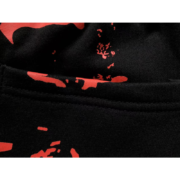 Close up view of the black Sp5der Sex AOP sweatpants showcasing the premium fabric texture and red graphic details.