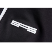 Close-up view of the iconic white embroidered Sp5der brand logo on the sleek black fabric of the G550 performance jacket.
