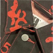 Close-up detail of the Sp5der 5ex AOP Denim Trucker Jacket showing the black denim fabric with a bold red all-over print.