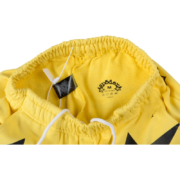 Interior view showing the brand label and sizing detail on the bright yellow Sp5der 5Star unisex sweatpants.