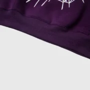 Close up view of the bottom hem and signature graphic on the Sp5der Web Hoodie in vibrant purple heavyweight cotton.
