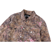 A close-up view of the Sp5der Trucker Jacket in Real Tree Camo print, featuring button closures and front pockets.