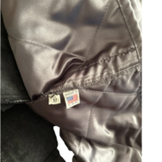 Close-up view of the interior tag on a premium Sp5der Worldwide jacket showing it is size M and Made In the USA.
