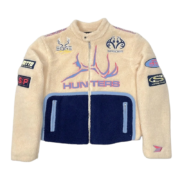 Front view of the beige and navy Sp5der Worldwide Hunters Sherpa Moto Jacket with branded patches and zipper.