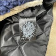 Detailed close-up of the interior brand tag featuring the iconic Sp5der web logo inside the Hunters Sherpa Moto Jacket.
