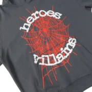 Close-up of the grey Sp5der x Heroes and Villains hoodie featuring a bold red spider web and stylized text graphic.