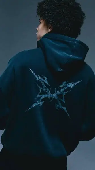 A model wearing a premium black Sp5der Arach hoodie, showcasing the detailed back graphic design and streetwear style.