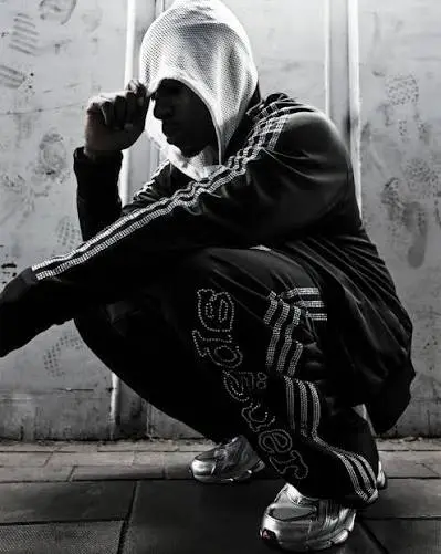 A person posing in a premium Sp5der tracksuit with a hoodie, showcasing bold street style fashion.