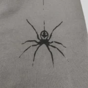A close-up view of the black signature spider web graphic print on the premium slate grey Sp5der 5Ex sweatpants fleece.