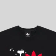 Close-up view of the black Sp5der x Adidas Souvenir Tee featuring the iconic trefoil logo and unique graphic print.