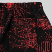 Close-up view of the back pocket detail on the black Sp5der Aop Web V2 sweatshort with red all-over web print design.