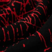 Close-up view of the black 13oz cotton fleece fabric featuring an all-over red web print on Sp5der Aop V2 sweatshorts.