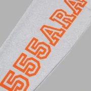 Close-up view of the Heather Grey Sp5der Arach hoodie sleeve featuring bold orange graphic text branding detail.