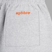 Close-up of the Sp5der Arach sweatpants in heather grey showing the branded back pocket detail in signature orange.