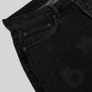 Close-up view of the faded black wash denim fabric and metallic hardware on the Sp5der Beluga Denim Archive pants.