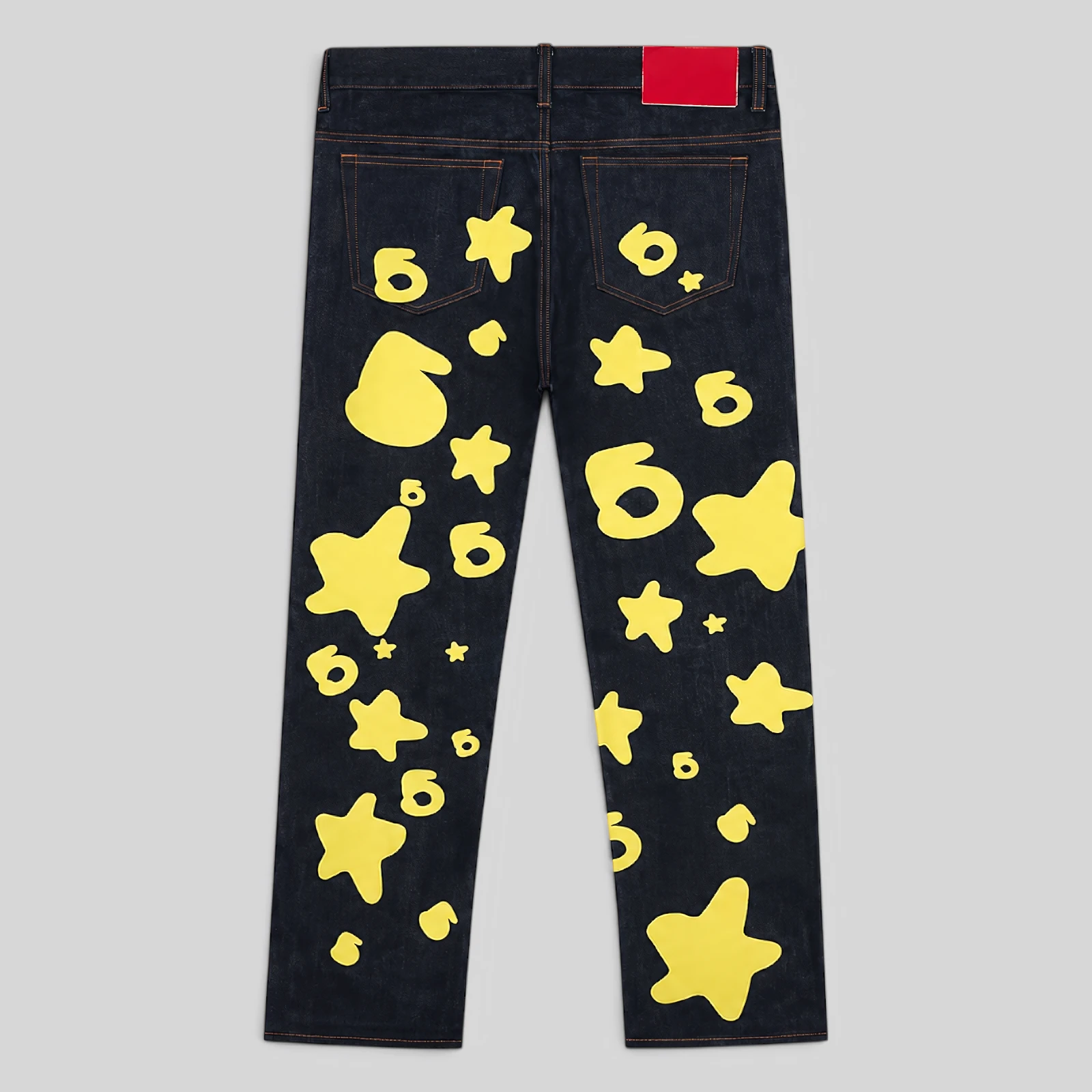 Back view of Sp5der Beluga Indigo Denim jeans featuring yellow star and graphic prints from the FW24 collection.