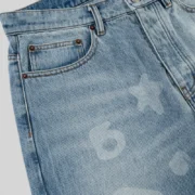 Close up view of the Sp5der Beluga Denim in Light Blue Wash featuring faded archive graphics and premium denim texture.