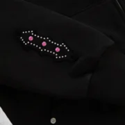 Close-up of the Sp5der Garibaldi Zip Up hoodie sleeve featuring intricate pink stone appliqué and studded details.
