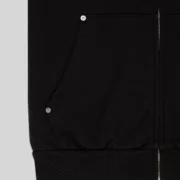 Close-up view of the metallic stud pocket detail on the black Sp5der Garibaldi zip-up hoodie made of heavy cotton fleece.