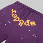Close-up view of the purple Sp5der OG Web V2 sweatpants featuring iconic yellow puff print web and star graphic details.